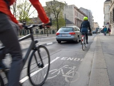 Fahrrad- und Autofahrer bewegen sich auf der Straße fort.